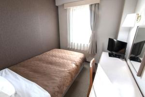 a small room with a bed and a television at Yono Daiichi Hotel in Saitama