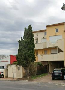a car parked in front of a building with a tree at Le recantou duplex in Marseillan