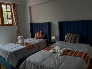 a bedroom with two beds with blue headboards at Pinkuylluna Lodge in Ollantaytambo