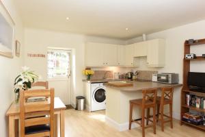 a kitchen with white cabinets and a table and chairs at The Wee Bothy at East Lothian Cottages in Lennoxlove