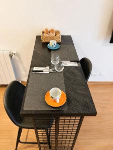 a black table with an orange plate and cups on it at Nuara Urban Loft in Novara +2 photos