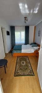 a bedroom with a bed and a rug on a wooden floor at Casuta din Crang in Moieciu de Jos
