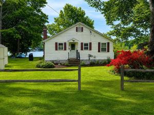 a small white house with a fence in a yard at Lakefront Retreat Home- Swimming-Fishing-Boating in Bethlehem