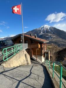 a canadian flag in front of a building with a mountain at Appartement entier dans chalet traditionnel in Bratsch
