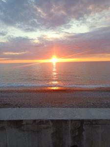 a sunset on the beach with the sun setting over the ocean at Happy house in Kobuleti