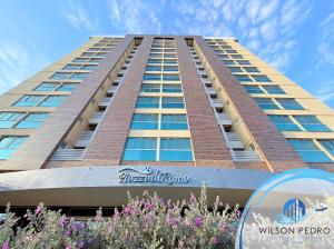 a tall building with purple flowers in front of it at Piazza diRoma - Acqua Park e Splash in Caldas Novas