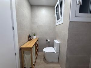 ein Badezimmer mit weißer Toilette und hölzerner Ablage. in der Unterkunft Farelleta in Llança + 4 Fotos