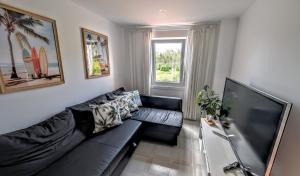 a living room with a black couch and a flat screen tv at Casa Carmen e do Hilario in Ponte Do Porto