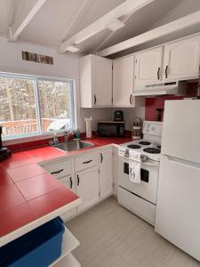 a kitchen with white cabinets and a white refrigerator at L'Opie in Saint Adolphe D'Howard +9 photos