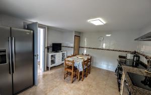 a kitchen with a table with chairs and a refrigerator at Casa Carmen e do Hilario in Ponte Do Porto