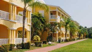 a yellow building with palm trees next to a sidewalk at Telamar Resort in Tela