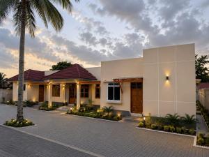a villa with a palm tree in front of a building at Nyumbani Executive Lodge in Ilala