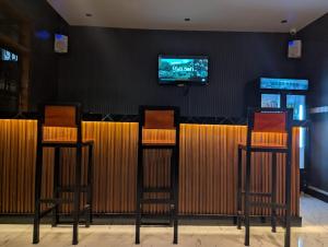 a bar with two chairs and a tv on the wall at Nyumbani Executive Lodge in Ilala