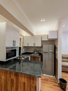 a kitchen with white cabinets and a stainless steel refrigerator at LuXURY STUDIOS MATROUH 3 in Marsa Matruh