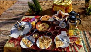 a table with food and drinks on top of a table at ERG MERZOUGA SAHARA CAMP in Merzouga
