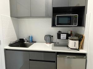 a small kitchen with a sink and a microwave at Eden on Beach in Palm Cove