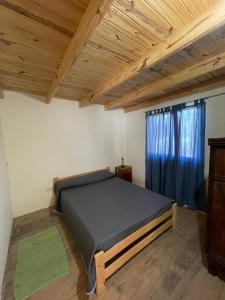 a bedroom with a bed and a wooden ceiling at Cabañas Aires de Campo II in Victoria