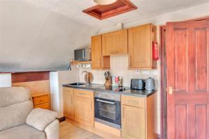 a small kitchen with wooden cabinets and a couch at Horseshoe Pass Holiday Lets in Llangollen