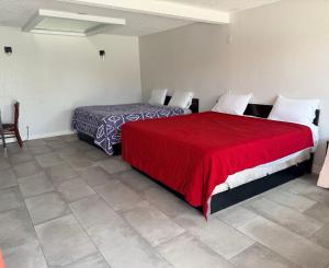 two beds in a room with a red blanket at Rocky Inn Motel in Lynwood +9 photos