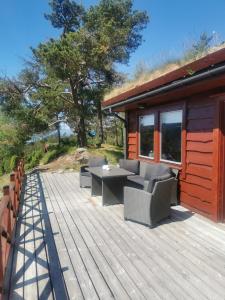 a deck with chairs and a table on a cabin at Cabin in Kvinnherad in Ølfernes