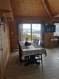 a dining room with a table and a large window at Cabin in Kvinnherad in Ølfernes