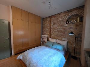 a bedroom with a bed and a brick wall at Homeric poems Suites in Chios