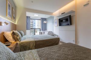 a hotel room with two beds and a television at Flat Central Arena Policia Federal in Brasília