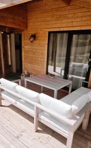 a patio with a table and white benches on a deck at Chalet romantique - Jacuzzi privatif - King size in Montignac-Charente +6 photos