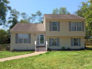 a yellow house with a porch and grass at Beach Hoppers' Hideaway in Cape Charles