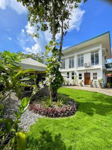 a house with a tree in the yard at KRUEGERs Cottage in Sipalay