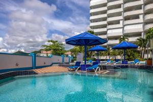 a swimming pool with blue chairs and umbrellas at Beachfront Condo in Simpson Bay, SXM - 2BR 2BA in Simpson Bay