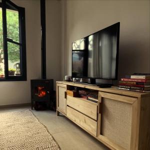 a flat screen tv on a wooden entertainment center with a fireplace at Casita colonial en Chapadmalal in Chapadmalal