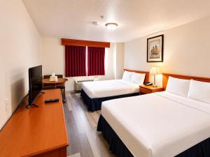 a hotel room with two beds and a television at Ace Inn in Fort McMurray