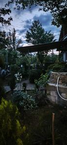 a garden with a stone wall and a pavilion at Mera Hostel in P'arts'khanaqanevi