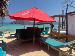 a red umbrella and chairs on a beach at Zulu beach in Cartagena de Indias +14 photos