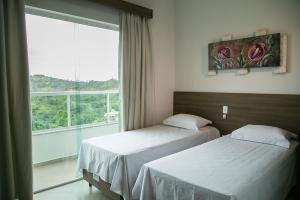 two beds in a room with a large window at Peçanha Grande Hotel in Peçanha +67 photos
