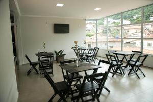 a dining room with tables and chairs and windows at Peçanha Grande Hotel in Peçanha