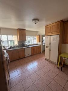 a kitchen with wooden cabinets and a white refrigerator at The Ardmore Home Share in Los Angeles