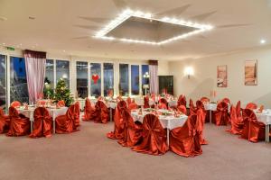 einen Bankettsaal mit Tischen, roten Stühlen und einem Tischler in der Unterkunft Hotel Dorotheenhof in Cottbus