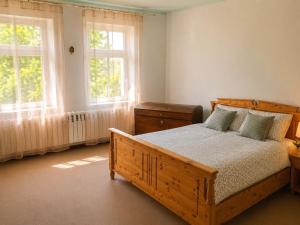 a bedroom with a wooden bed and two windows at Ferienhaus Schorfheide Kamin Sauna Naturgarten nahe Seen & Wildpark in Schorfheide