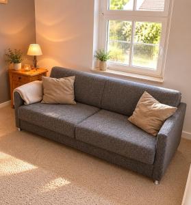 a gray couch in a living room with a window at Ferienhaus Schorfheide Kamin Sauna Naturgarten nahe Seen & Wildpark in Schorfheide