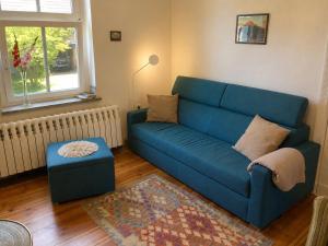 a living room with a blue couch and a ottoman at Ferienhaus Schorfheide Kamin Sauna Naturgarten nahe Seen & Wildpark in Schorfheide