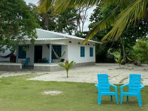 two blue chairs sitting in front of a house at Donde Andres en la Playa in Necoclí