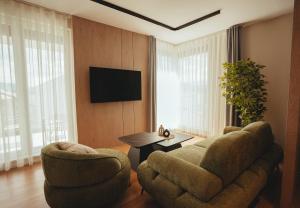 ein Wohnzimmer mit zwei Sesseln und einem Flachbildfernseher in der Unterkunft Noir Hotel in Gjakove