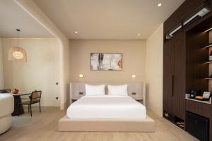 a bedroom with a white bed and a table at The Lario Collection - A Wellness Resort in Seminyak