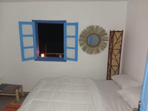 a bedroom with a bed and a window with a mirror at Sharing is caring Taghazout in Taghazout