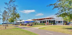 a building with tables and umbrellas in a park at Beachfront Bliss Studio Apt on the Foreshore in Nightcliff