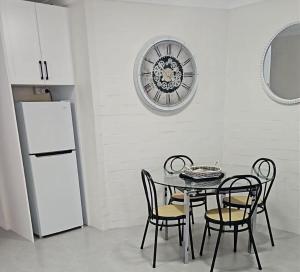 a kitchen with a table and chairs and a clock on the wall at Avocet Apartment in Perth