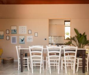 a dining room with a table and white chairs at Villa Panoramica Sunset House in Torre Vado