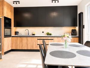 a kitchen with black cabinets and a table with flowers at Apartament Niebo przy plaży ROYAL APARTS OSTRÓDA in Ostróda